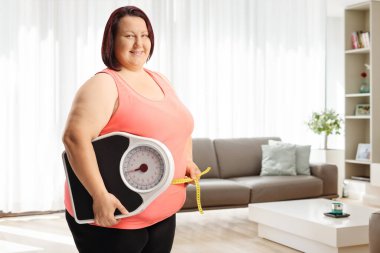 Kilo ölçeği ve bel ölçüsü tutan şişman bir kadın.