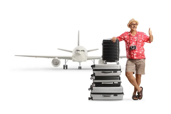 白い背景に隔離された空港でスーツケースの山にもたれかかっている成熟した男の完全な長さの肖像画 — ストック写真