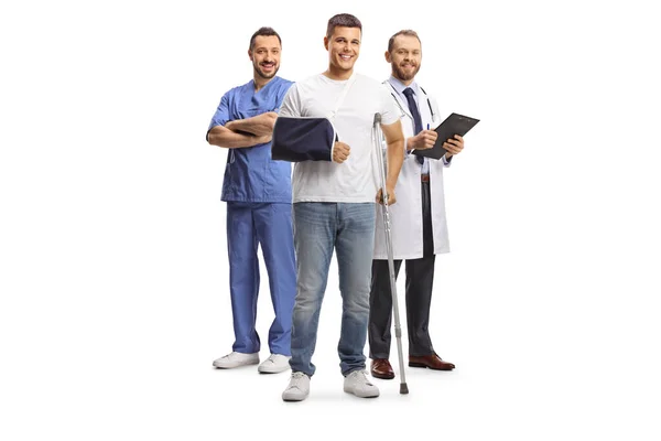 Young Man Crutches Arm Sling Standing Front Medical Team Isolated — Stock Photo, Image