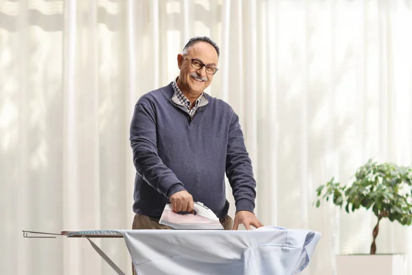 Reifer Mann Bügelt Hemd Und Lächelt Hause — Stockfoto