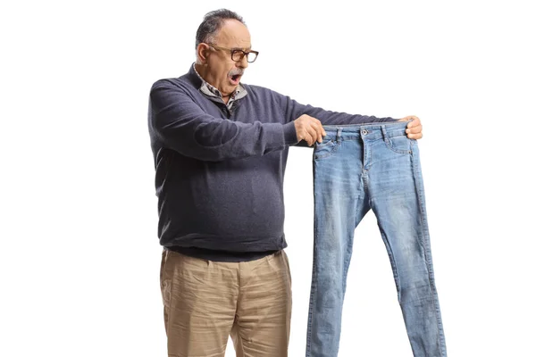 Chockad Mogen Man Håller Ett Par Små Jeans Isolerade Vit — Stockfoto