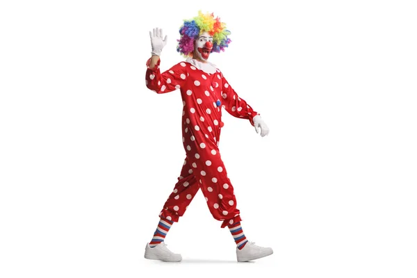 一个穿着红色服装的小丑在白色背景下走起路来挥手的全景镜头 — 图库照片