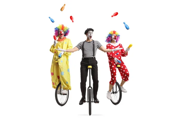 两只小丑和一只哑剧小丑骑着自行车 在白色的背景上独自跳着杂耍 — 图库照片