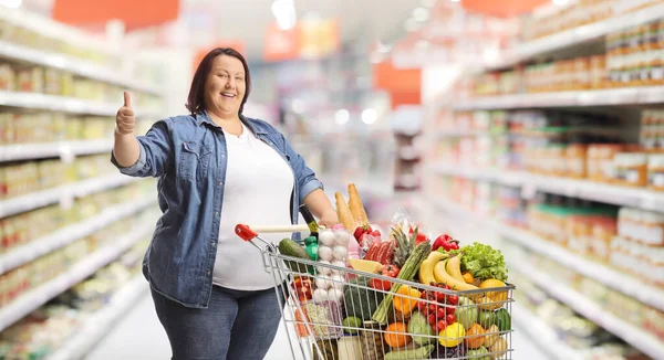 Túlsúlyos Egy Szupermarketben Bevásárlókocsival Feltartott Hüvelykujjal — Stock Fotó
