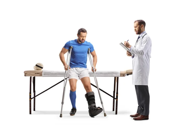 白い背景に隔離された松葉杖で歩く 理学療法を練習する怪我を持つサッカー選手 — ストック写真