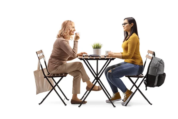 一个成熟的女人和一个女学生坐在桌旁 喝着被白色背景隔离的咖啡 — 图库照片
