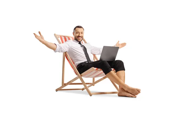 白い背景に隔離された彼の膝の上にコンピュータとデッキチェアに座っているビジネスマン — ストック写真