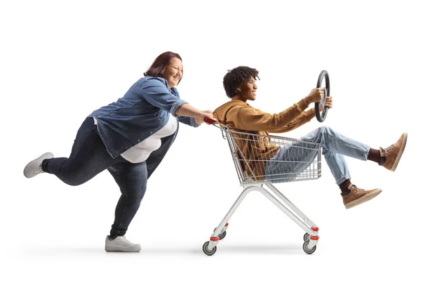 フル長さプロフィールショットのA太りすぎ女性プッシュAアフリカ系アメリカ人男中にショッピングカート隔離された上の白い背景 — ストック写真