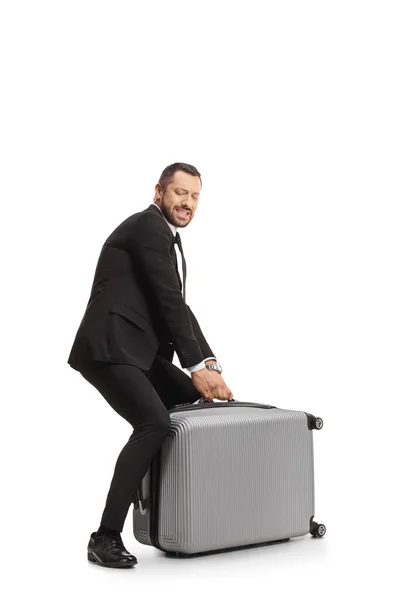 白い背景に隔離された重いスーツケースを持ち上げようとしているビジネスマンの完全な長さのショット — ストック写真