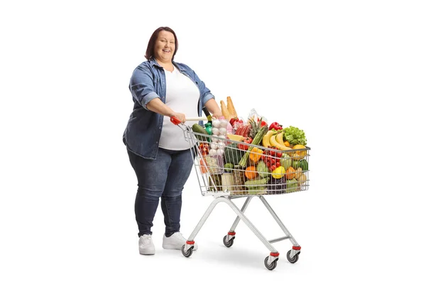 白い背景に隔離された完全なショッピングカートで立って太りすぎの女性の完全な長さのショット — ストック写真