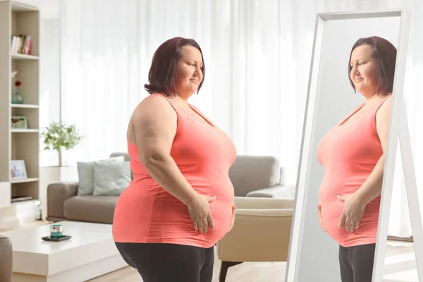 Übergewichtige Frau Hält Ihren Bauch Und Schaut Den Spiegel — Stockfoto