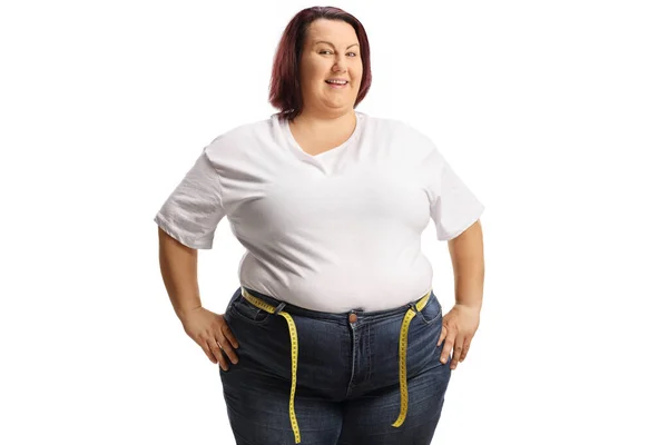 穿着牛仔裤 腰围有测量带的肥胖女人对着被白色背景隔离的相机笑着 — 图库照片