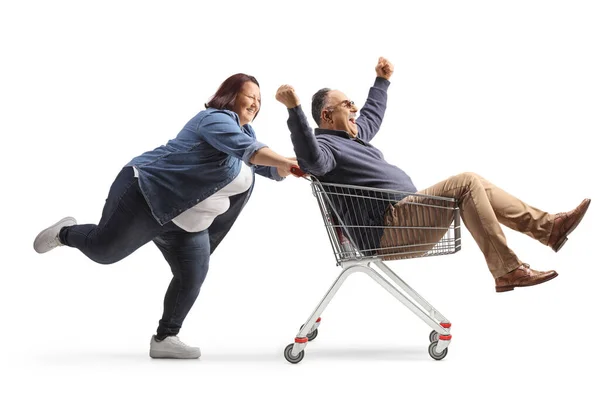 白い背景に隔離されたショッピングカートの中に杖を持つ幸せな成熟した男を押す女性の完全な長さのプロフィールショット — ストック写真