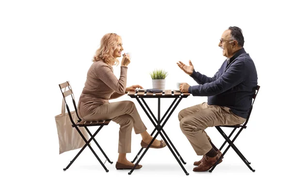 熟女と女性はテーブルの上に座って話をし 白の背景に隔離されたコーヒーを飲みます — ストック写真