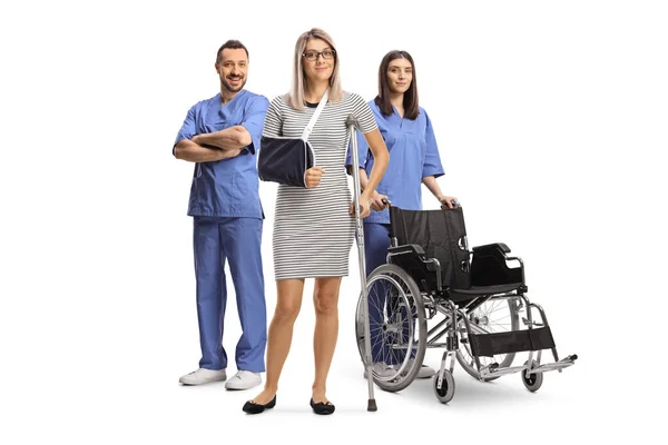 白い背景に隔離された医療従事者の前に負傷した腕と足の立っている女性 — ストック写真