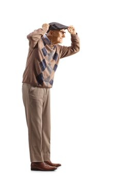 Full length profile shot of a elderly gentleman putting on a hat isolated on white background