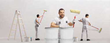 House painters with paint rollers and a ladder painting a wall