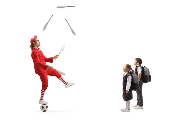 赤いスーツの男がボールの上に立って 白い背景に隔離されたジャグリングを見ている子供たち — ストック写真