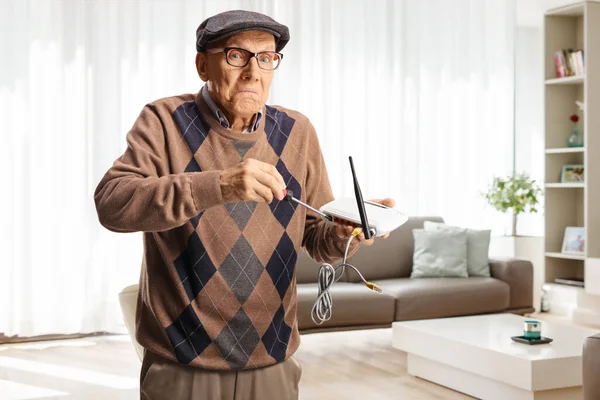 Zabawny Staruszek Naprawiający Router Śrubokrętem Domu Salonie — Zdjęcie stockowe