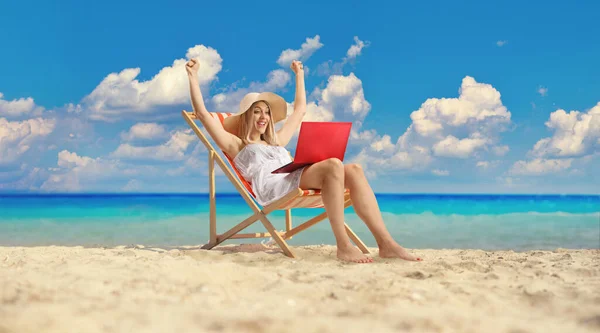 身穿白色连衣裙的年轻漂亮的女人坐在沙滩上 手里拿着笔记本电脑 — 图库照片