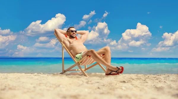 Mayolu Güneş Gözlüklü Genç Adam Plaj Sandalyesinde Oturuyor — Stok fotoğraf