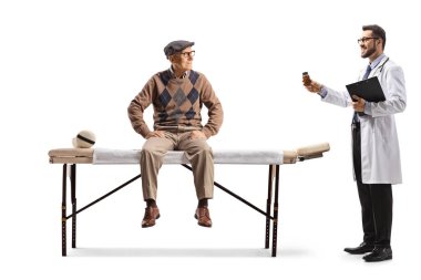 Fizyoterapi yatağında oturan yaşlı bir adam ve beyaz arka planda izole edilmiş bir ilaç şişesi gösteren bir doktor.