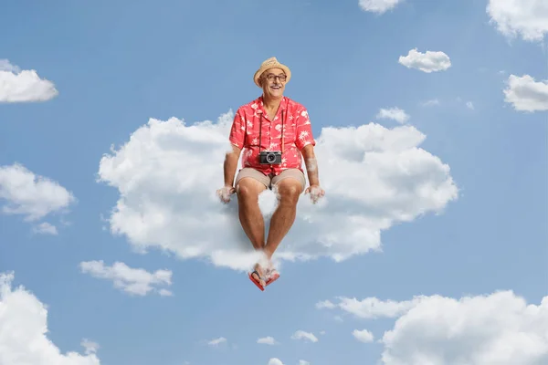 雲の上に座っている彼の首の周りにぶら下がっているカメラと幸せな成熟した男性の観光客 — ストック写真