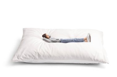 Beyaz arka planda izole edilmiş büyük bir yastıkta dinlenen kot pantolonlu genç bir kadının tam boy fotoğrafı.