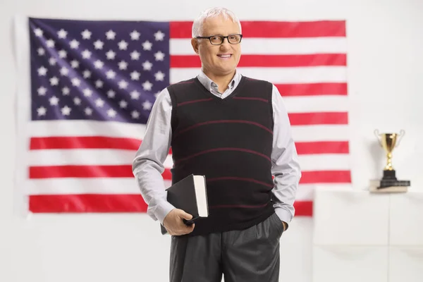 Erkek Profesör Bir Kitap Tutuyor Amerikan Bayrağının Önünde Gülümsüyor — Stok fotoğraf