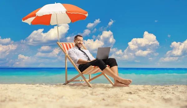 Kumsalda Şemsiyenin Altında Dizüstü Bilgisayarla Eğlenen Bir Adamı — Stok fotoğraf