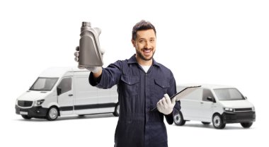 Otomobil tamircisi beyaz arka planda izole edilmiş minibüslerin önünde bir şişe motor yağı tutuyor.