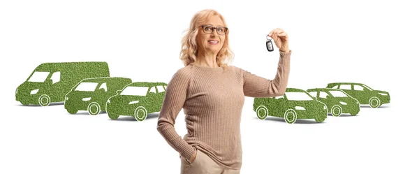Starší Žena Drží Klíč Před Zelenými Ekologicky Šetrné Automobily Izolované — Stock fotografie