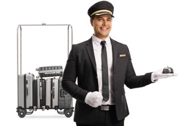 Bellboy, beyaz arka planda izole edilmiş bavullarla bir arabanın önünde bir resepsiyon zili tutuyor.