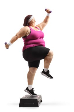 Beyaz arka planda izole halterlerle aerobik yapan kilolu bir kadın.