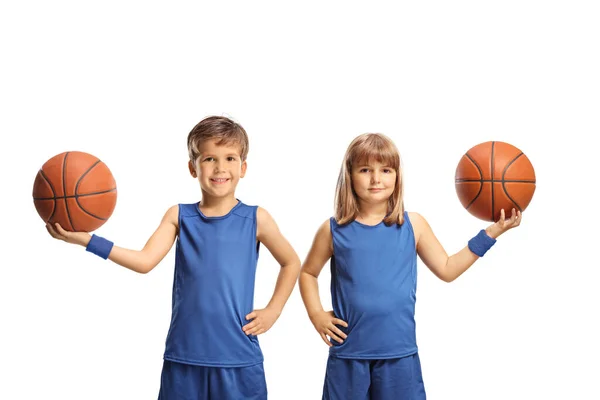 青いスポーツジャージの男の子と女の子は 白い背景に隔離されたカメラでバスケットボールと微笑みを保持しています — ストック写真