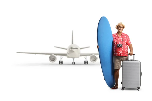白い背景に隔離された空港でサーフボードとスーツケースを保持する成熟した男性の観光客 — ストック写真