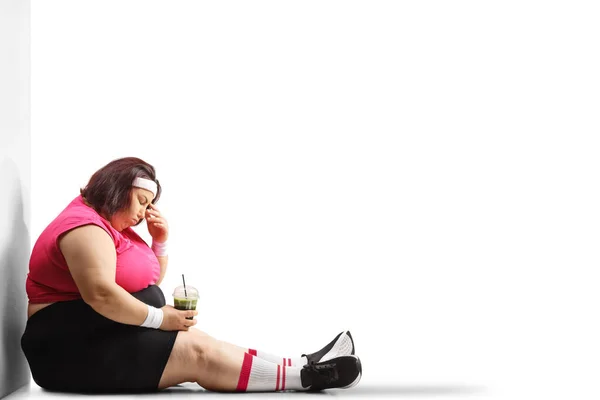 健康な緑を保持し 白い背景に隔離された地面に座っている抑圧された太りすぎの女性 — ストック写真
