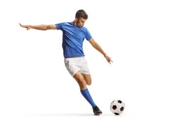 Mavi formalı bir futbolcu beyaz arka planda izole edilmiş bir topa vurmaya hazırlanıyor.