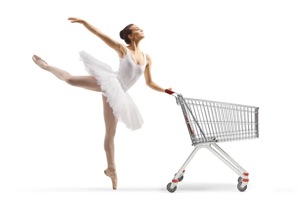 白いチュートゥのドレスダンスでバレリーナのフル長さのプロフィールショットと白い背景に隔離されたショッピングカートを保持 — ストック写真