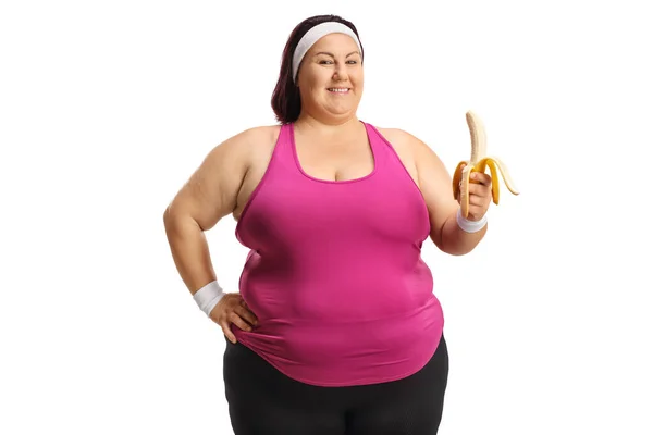 白い背景に隔離されたバナナを保持するスポーツウェアの太りすぎの女性 — ストック写真