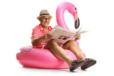 Olgun bir adam flamingo yüzme ringinde oturuyor ve beyaz arka planda izole edilmiş bir gazete okuyor.