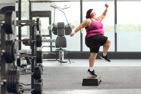 ジム内のステップエアロビクスを行っている太りすぎの女性の全長のプロフィールショット — ストック写真
