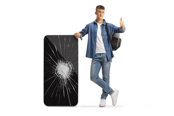 Mężczyzna Student Plecakiem Opierając Się Zepsuty Telefon Komórkowy Gestykulując Kciuki — Zdjęcie stockowe