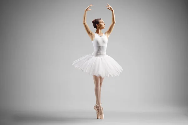 灰色の背景に隔離された腕で踊る白いドレスのバレリーナ — ストック写真