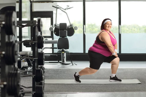 穿着运动服的胖女人在体育馆里伸懒腰 — 图库照片