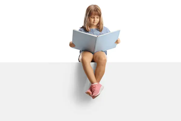 小女孩坐在一块空白的板子上 阅读一本以白色背景为背景的书 — 图库照片