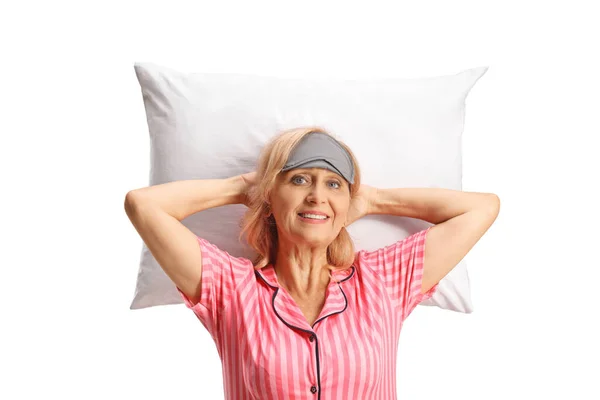 一个穿着睡衣 戴着睡眠面具的成熟女人躺在白色背景的枕头上的画像 — 图库照片