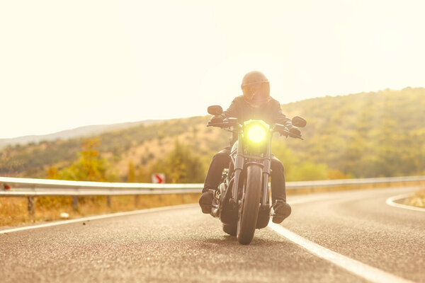 Человек в шлеме на мотоцикле на открытой дороге на закате