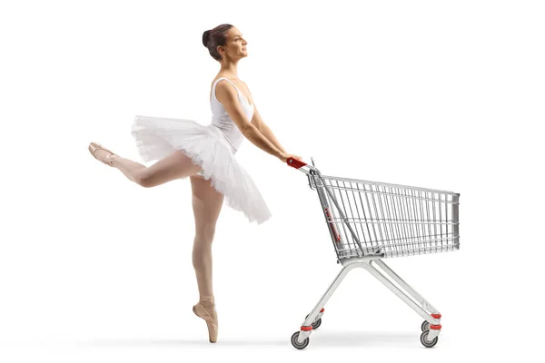 白いチュートゥのドレスダンスでバレリーナのフル長さのプロフィールショットと白い背景に隔離されたショッピングカートを押す — ストック写真