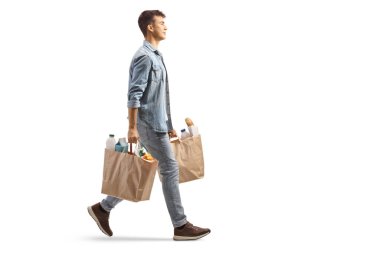 Beyaz arka planda izole edilmiş market poşetleri taşıyan bir gencin tam boy profil fotoğrafı.